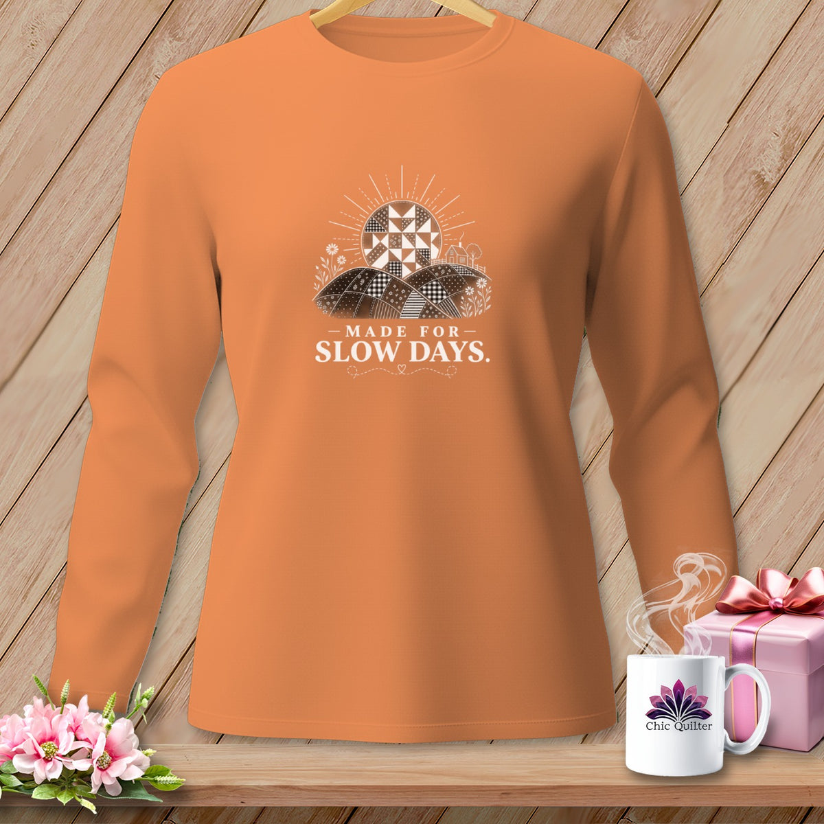 Orange long-sleeve shirt with a graphic of a patchwork sun and hills reading "Made for Slow Days."