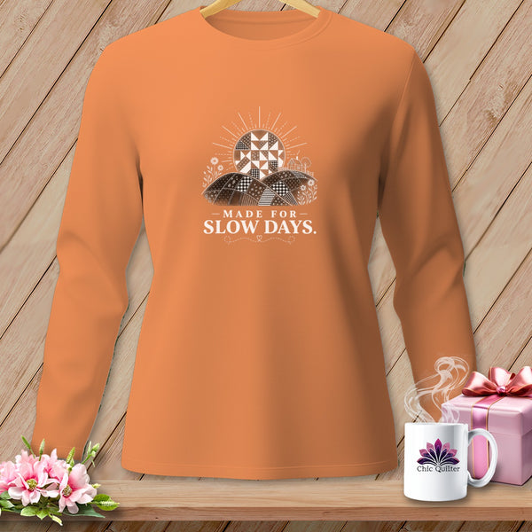 Orange long-sleeve shirt with a graphic of a patchwork sun and hills reading "Made for Slow Days."