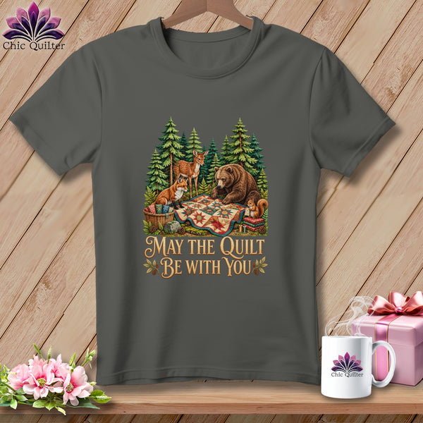 Charcoal t-shirt featuring a forest scene with woodland animals gathered around a colorful quilt and the text "May The Quilt Be With You".