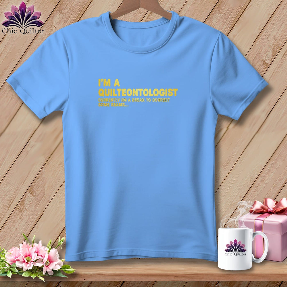 Light blue t-shirt with yellow text: "I'M A QUILTEONTOLOGIST CURRENTLY ON A BREAK TO CORRECT SOME SEAMS..."