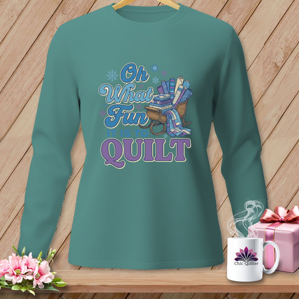 Teal long-sleeve shirt with "Oh What Fun It Is To Quilt" text and quilting supplies on a sleigh.