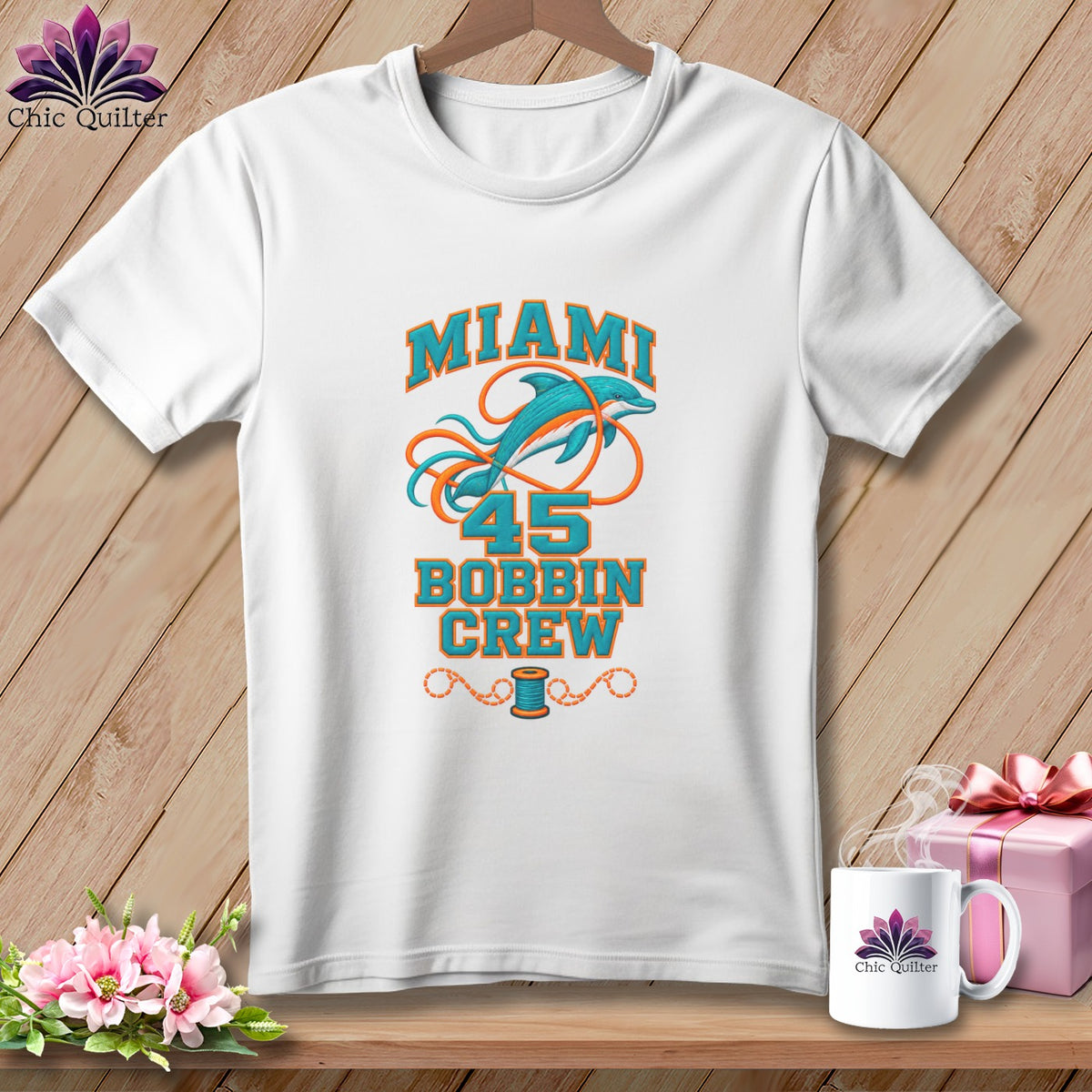A white t-shirt hanging on a wooden wall features a graphic with a dolphin, the number 45, and the text Miami Bobbin Crew.