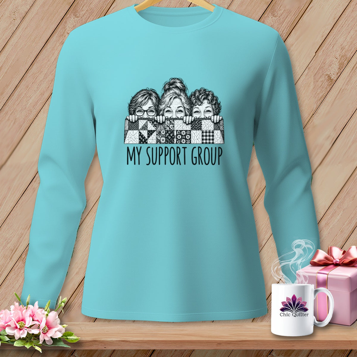 Teal long-sleeve shirt with graphic of three women peeking over quilt, text reads "MY SUPPORT GROUP".