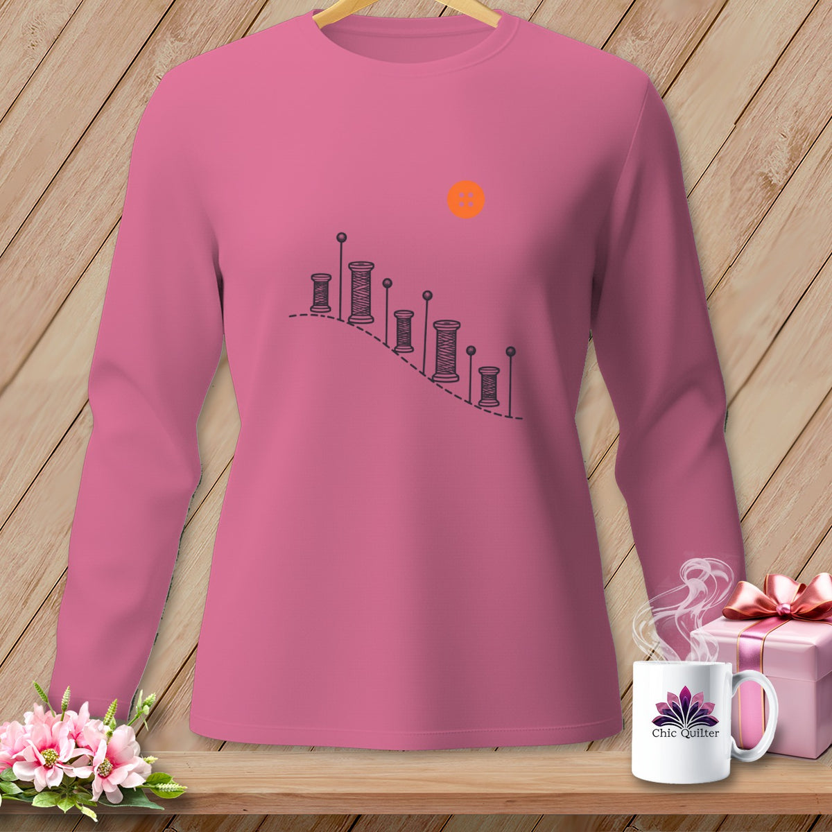 Pink long-sleeve shirt with sewing spool graphic and orange sun.