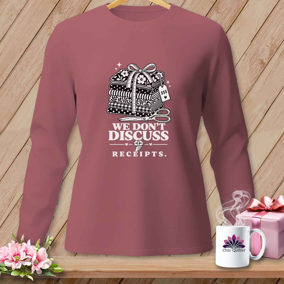 Long sleeve shirt with stack of fabrics, scissors, and text "We Don't Discuss Receipts."