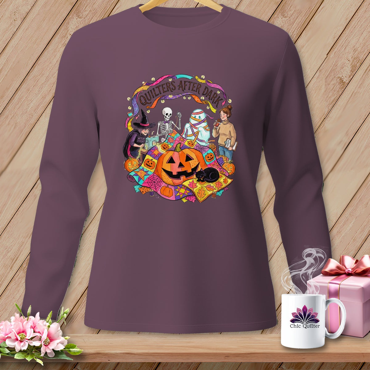 Quilters After Dark Halloween graphic on purple long-sleeve shirt with pumpkin, skeleton, mummy, and witch.