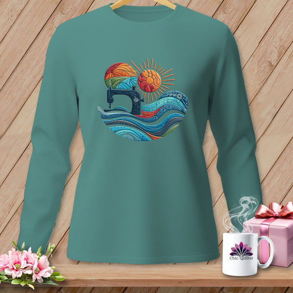 Teal long-sleeve shirt with sewing machine, sun, and colorful fabric design.