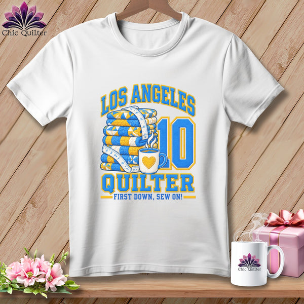 A white t-shirt features graphic text reading LOS ANGELES QUILTER with a stacked quilt and a coffee mug.