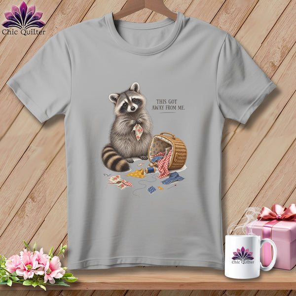 Grey t-shirt with a raccoon holding fabric and sewing supplies. Text reads "This Got Away From Me."