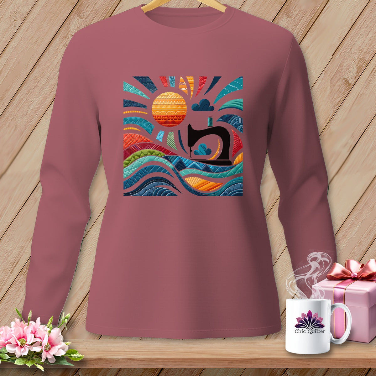 Pink long-sleeve shirt with a colorful sewing-themed sun and waves graphic.