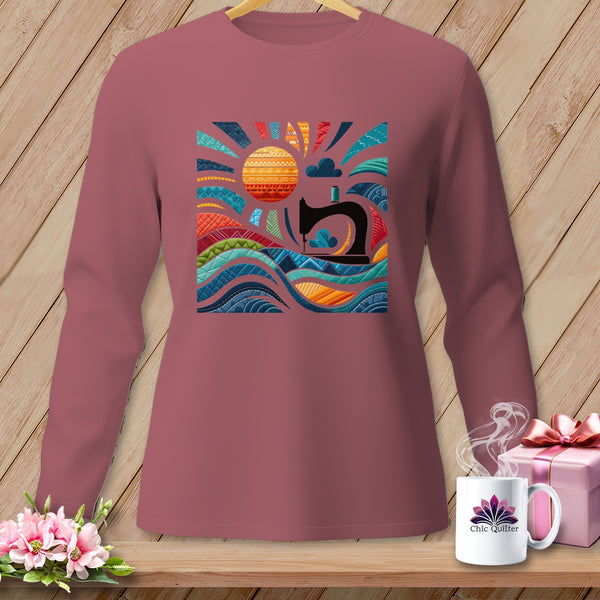 Pink long-sleeve shirt with a colorful sewing-themed sun and waves graphic.