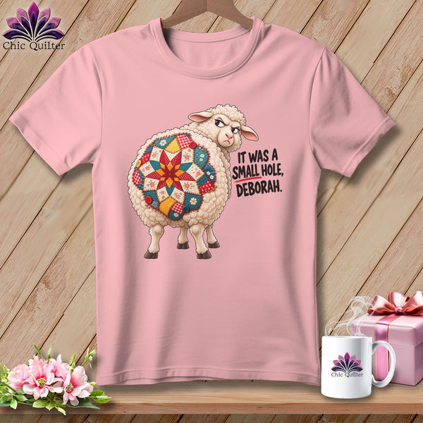 Pink t-shirt with a grumpy sheep wearing a quilt pattern on its back.