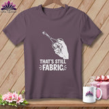 Purple t-shirt with graphic of hand holding scissors cutting fabric and text 