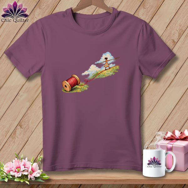 A purple t-shirt featuring a graphic of a person walking on a red thread.