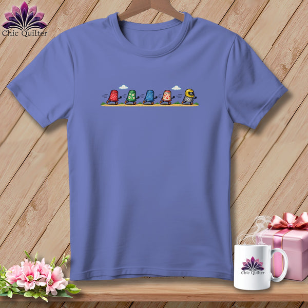 Periwinkle t-shirt featuring a cartoon graphic of five thimbles running across a path.