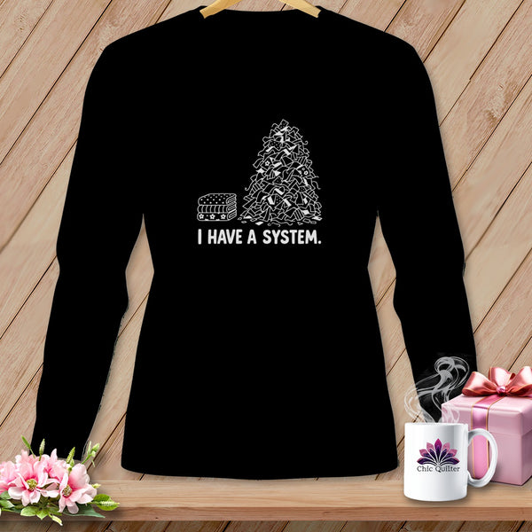 Black long sleeve shirt with a graphic of fabric stacks and text "I HAVE A SYSTEM."