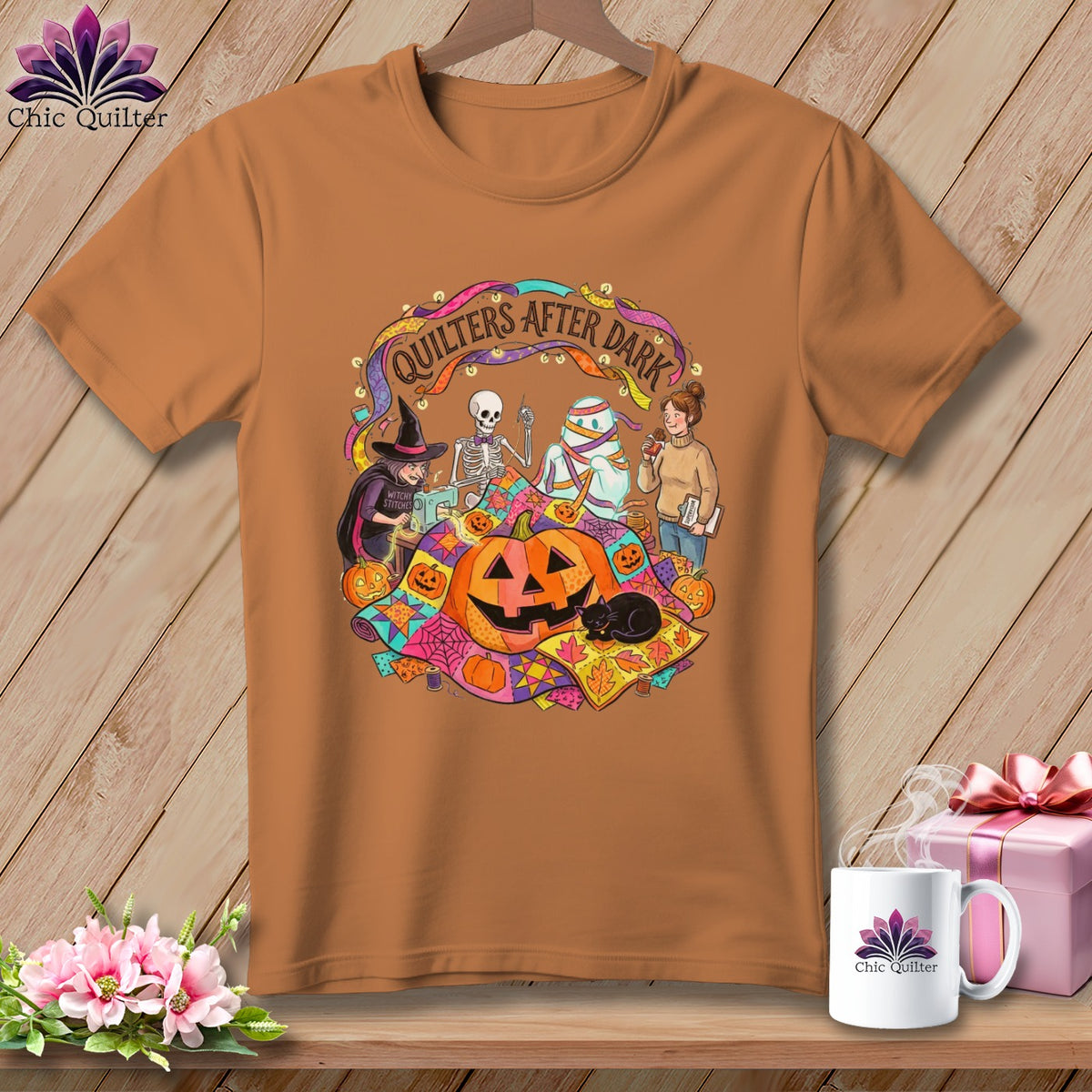 T-shirt featuring "Quilters After Dark" Halloween graphic with witch, skeleton, mummy, and pumpkins.
