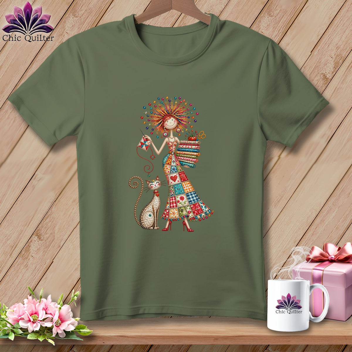 An olive green t-shirt displays an illustration of a woman in a patchwork dress with a cat.