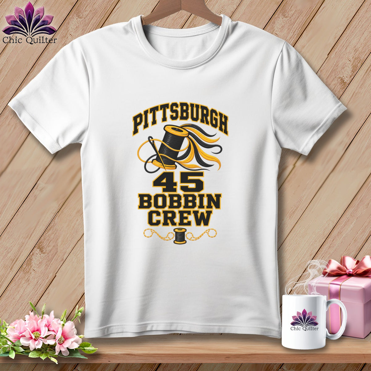 A white crewneck t-shirt featuring a black and yellow graphic with a spool of thread and the text "Pittsburgh 45 Bobbin Crew."