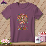 Plum short-sleeve t-shirt featuring a colorful whimsical illustration of a girl holding folded quilts.