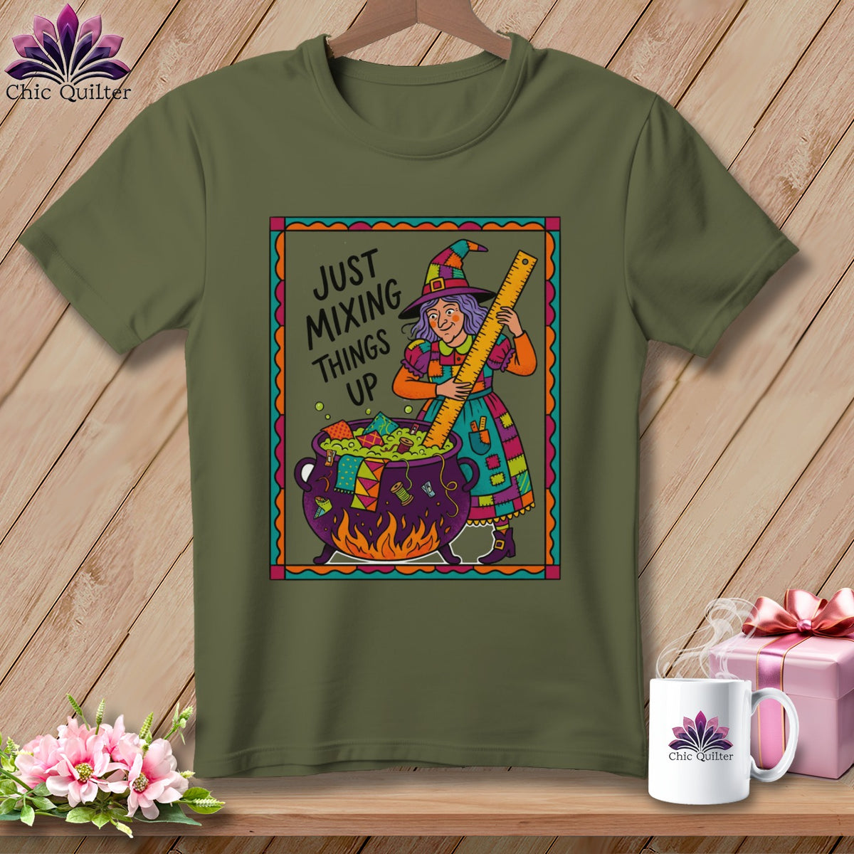 Green t-shirt with a cartoon witch stirring a cauldron with a ruler, text "JUST MIXING THINGS UP".