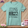 Light blue t-shirt with black text and sewing graphics: "IT'S NOT CLUTTER IF IT'S FABRIC".