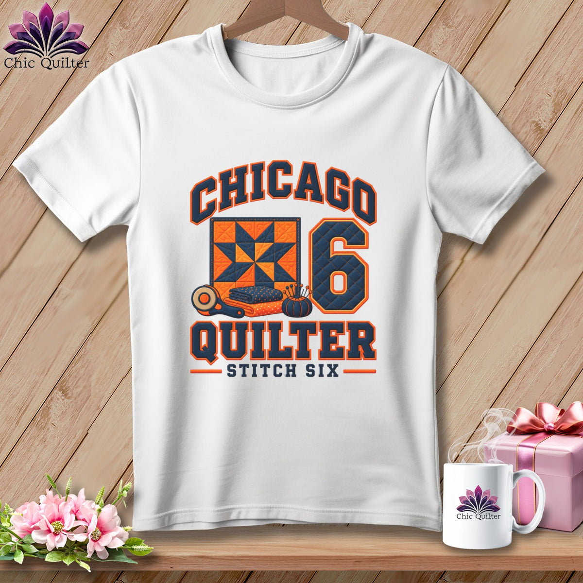 A white t-shirt hanging against a wooden background features a graphic with the text Chicago Quilter Stitch Six.