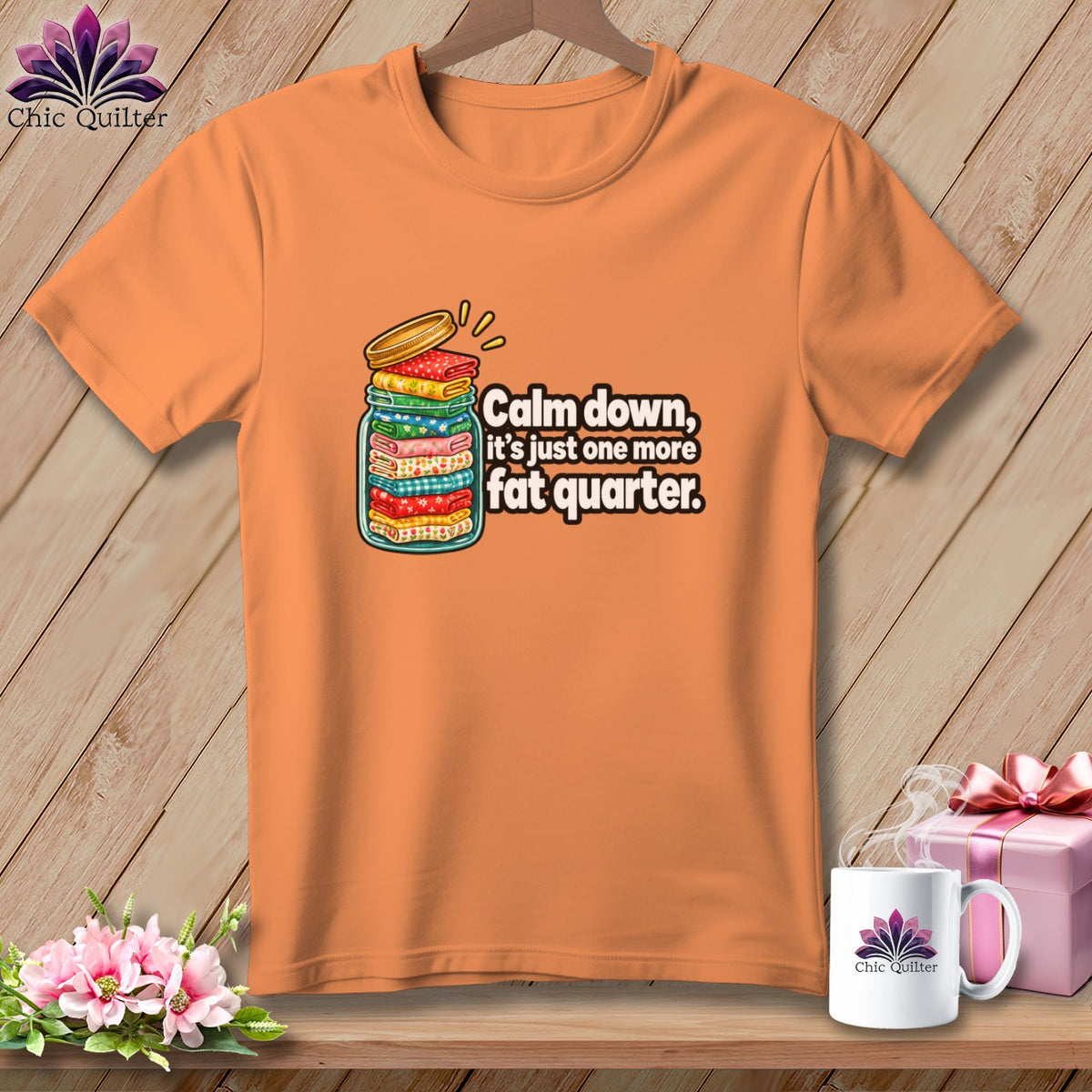 Orange t-shirt featuring a graphic of a jar full of folded fabric with text reading "Calm down, it's just one more fat quarter."