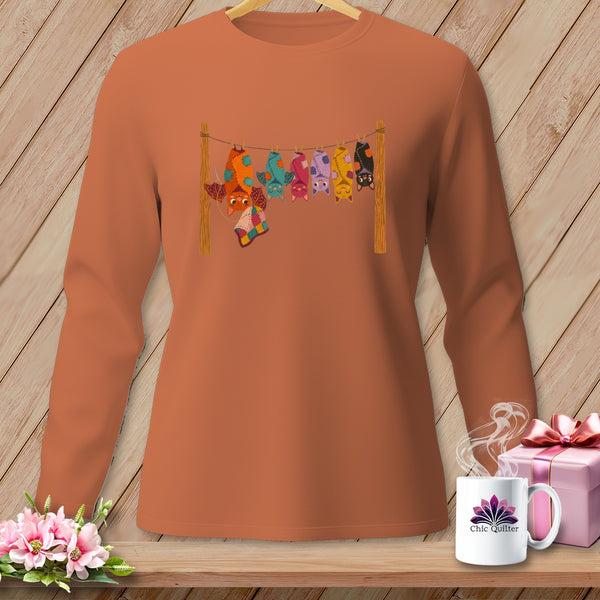 Orange long-sleeve shirt with a graphic of colorful bats hanging on a clothesline.