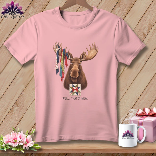 Pink t-shirt with a moose holding quilt scraps and a quilt square, text reads WELL. THAT'S NEW.