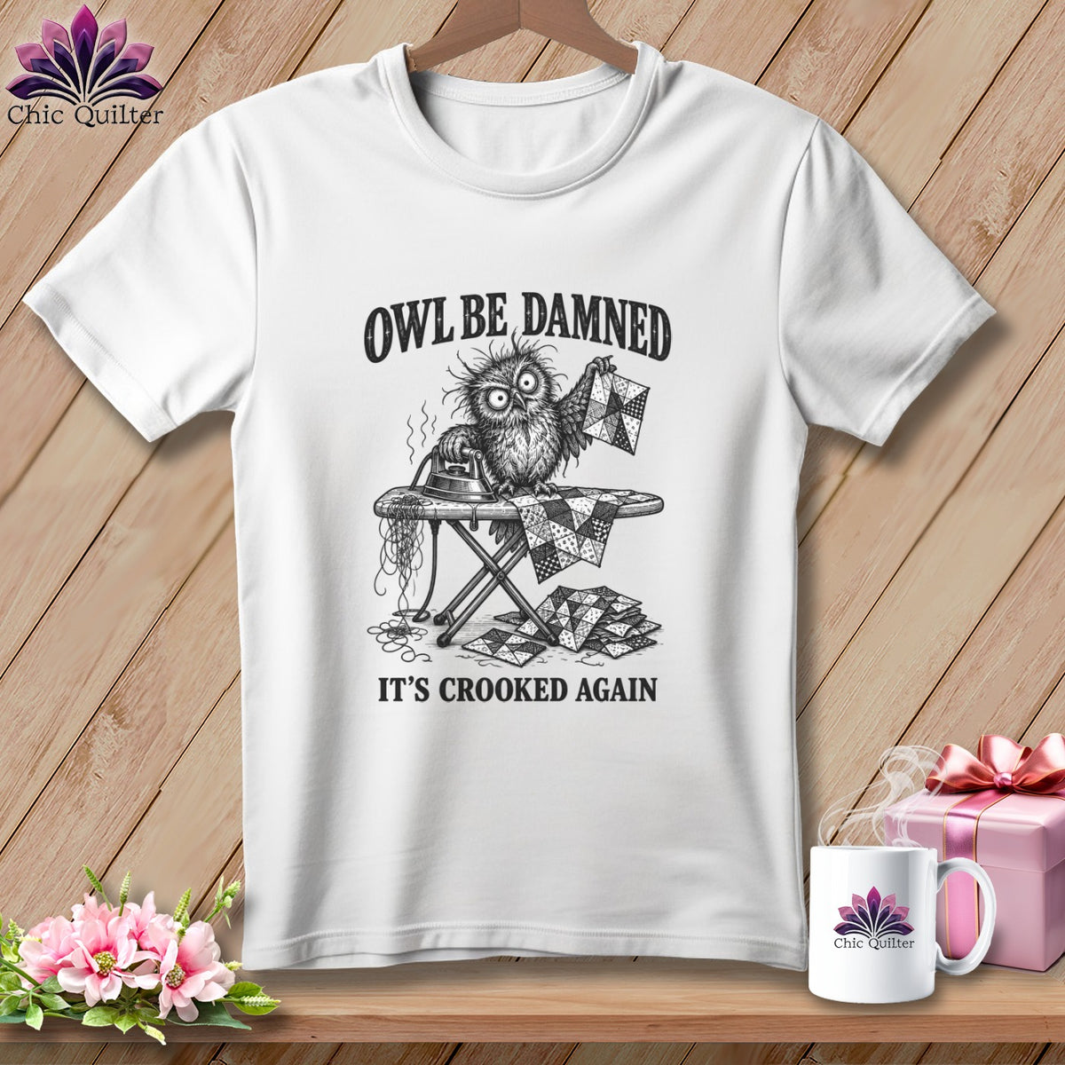 White t-shirt featuring a distressed owl on an ironing board with text: "OWL BE DAMNED IT'S CROOKED AGAIN".