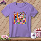 Purple t-shirt featuring a graphic of cartoon farm animals peeking over a colorful patchwork quilt.