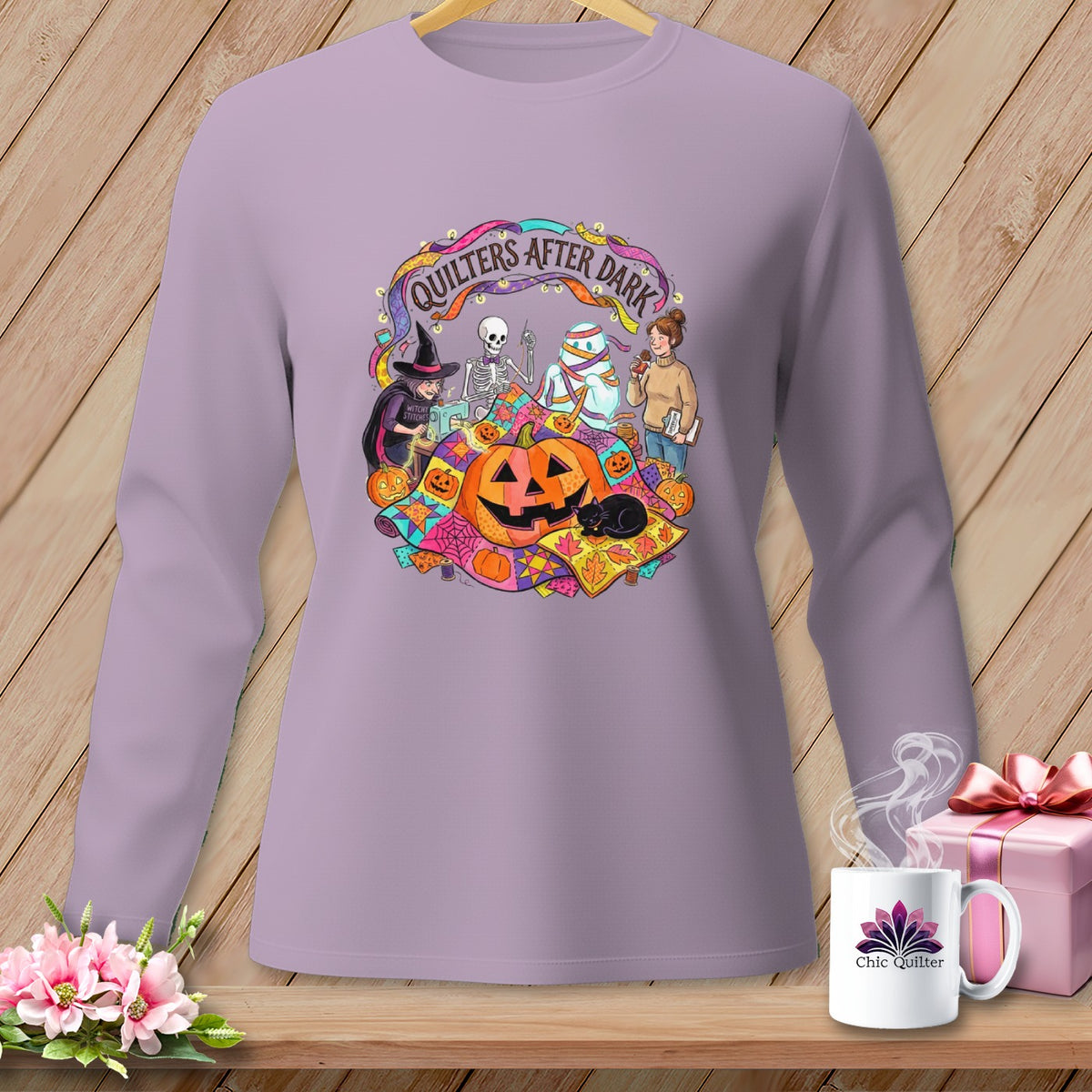 Quilters After Dark graphic on a lavender long-sleeve shirt featuring Halloween characters and pumpkins.
