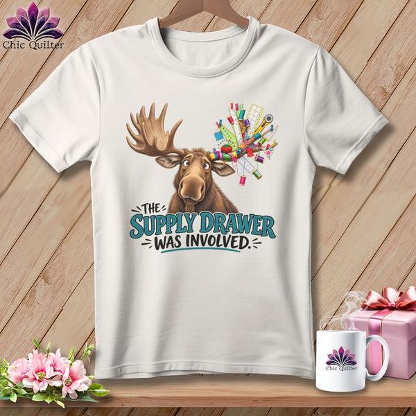 White t-shirt with cartoon moose and sewing supplies, text reads "The Supply Drawer Was Involved."