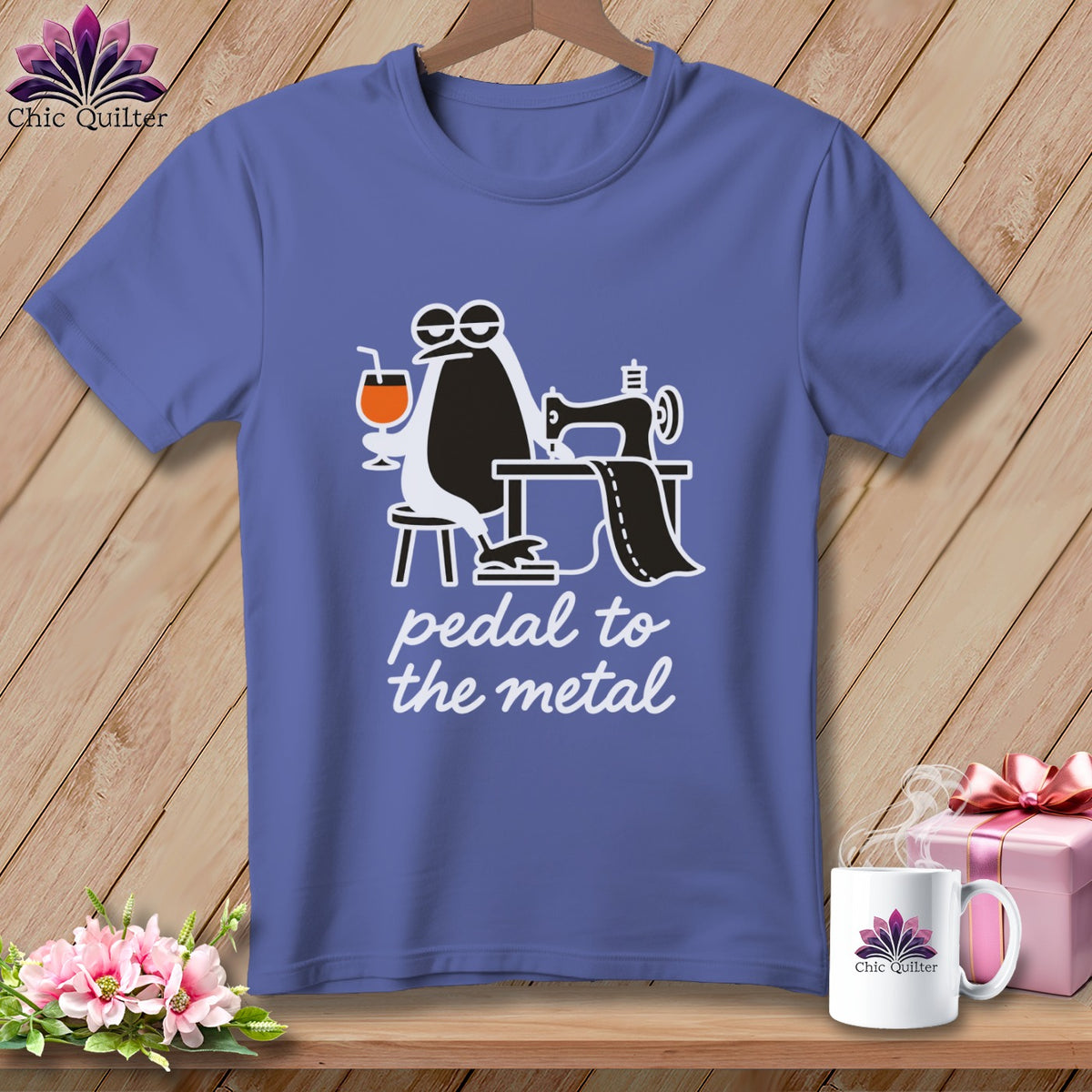 Purple t-shirt with cartoon penguin at sewing machine, holding a drink, and text "pedal to the metal".