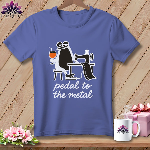 Purple t-shirt with cartoon penguin at sewing machine, holding a drink, and text "pedal to the metal".