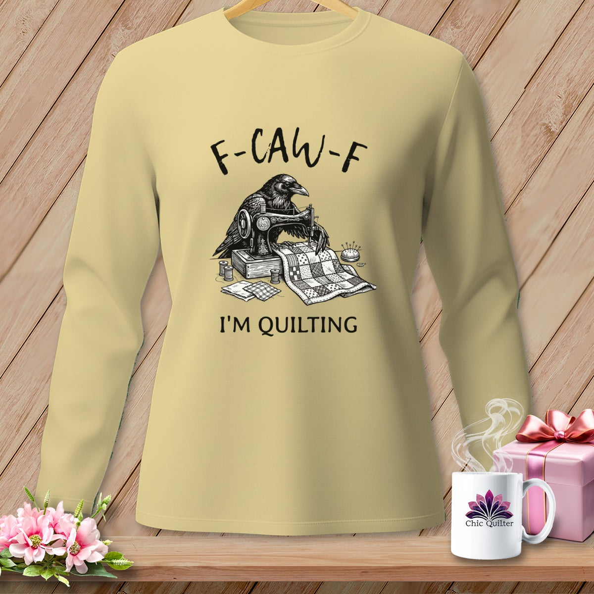 Light yellow sweatshirt with a crow sewing a quilt, reading "F-CAW-F I'M QUILTING".