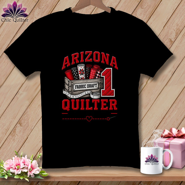 Black t-shirt featuring a quilting graphic with a crate of fabric, the number one, and red text reading Arizona Quilter.
