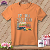 An orange t-shirt printed with the text I'm That Quilt Friend, stacked fabrics, pins, and a rotary cutter.