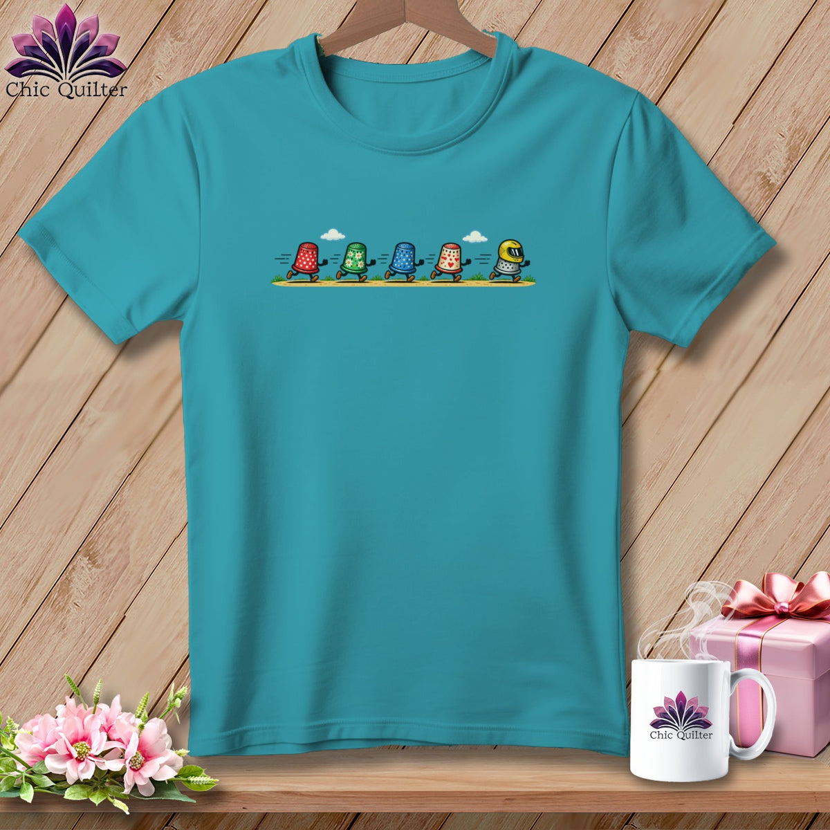 A turquoise crewneck t-shirt featuring a graphic of five running thimbles with different patterns.