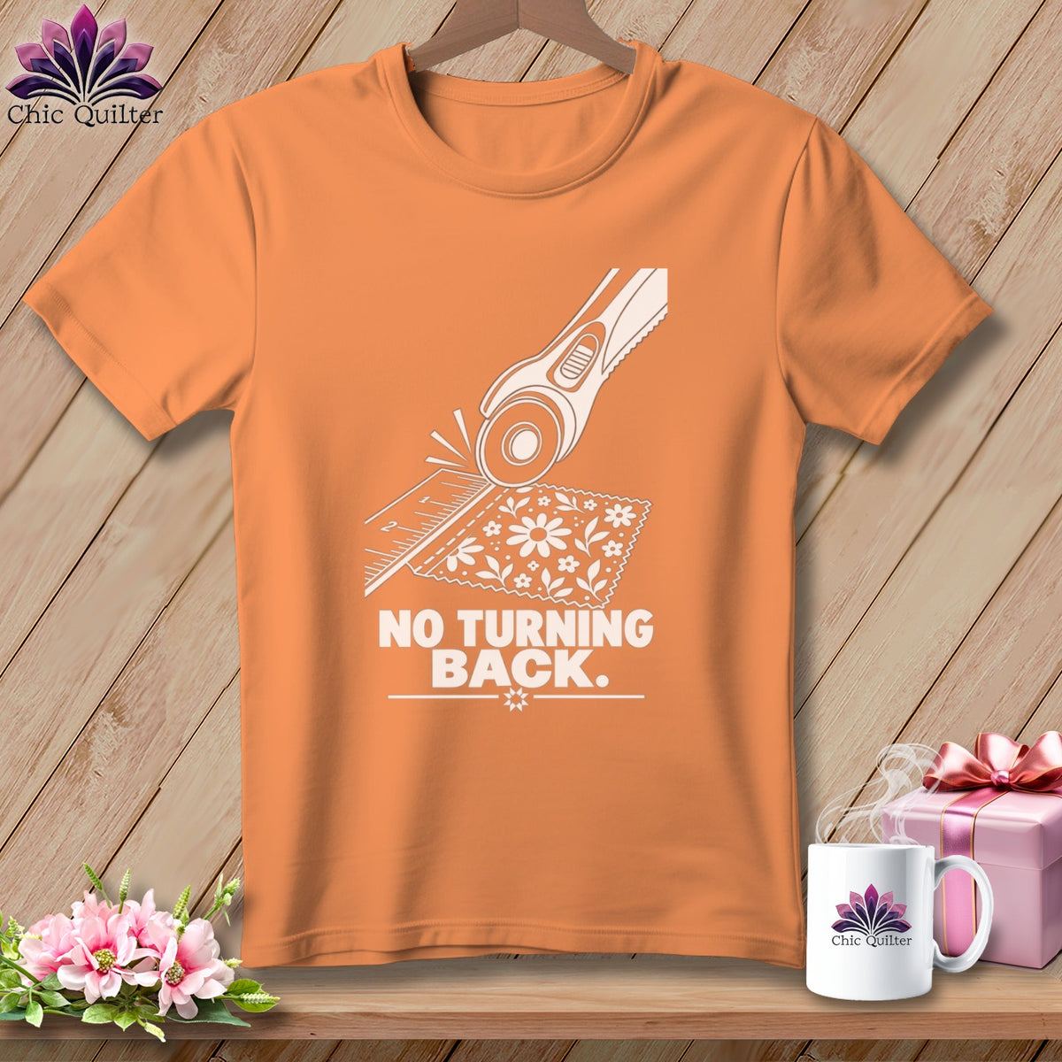 Orange t-shirt with white graphic of rotary cutter, ruler, and fabric, reading "NO TURNING BACK."