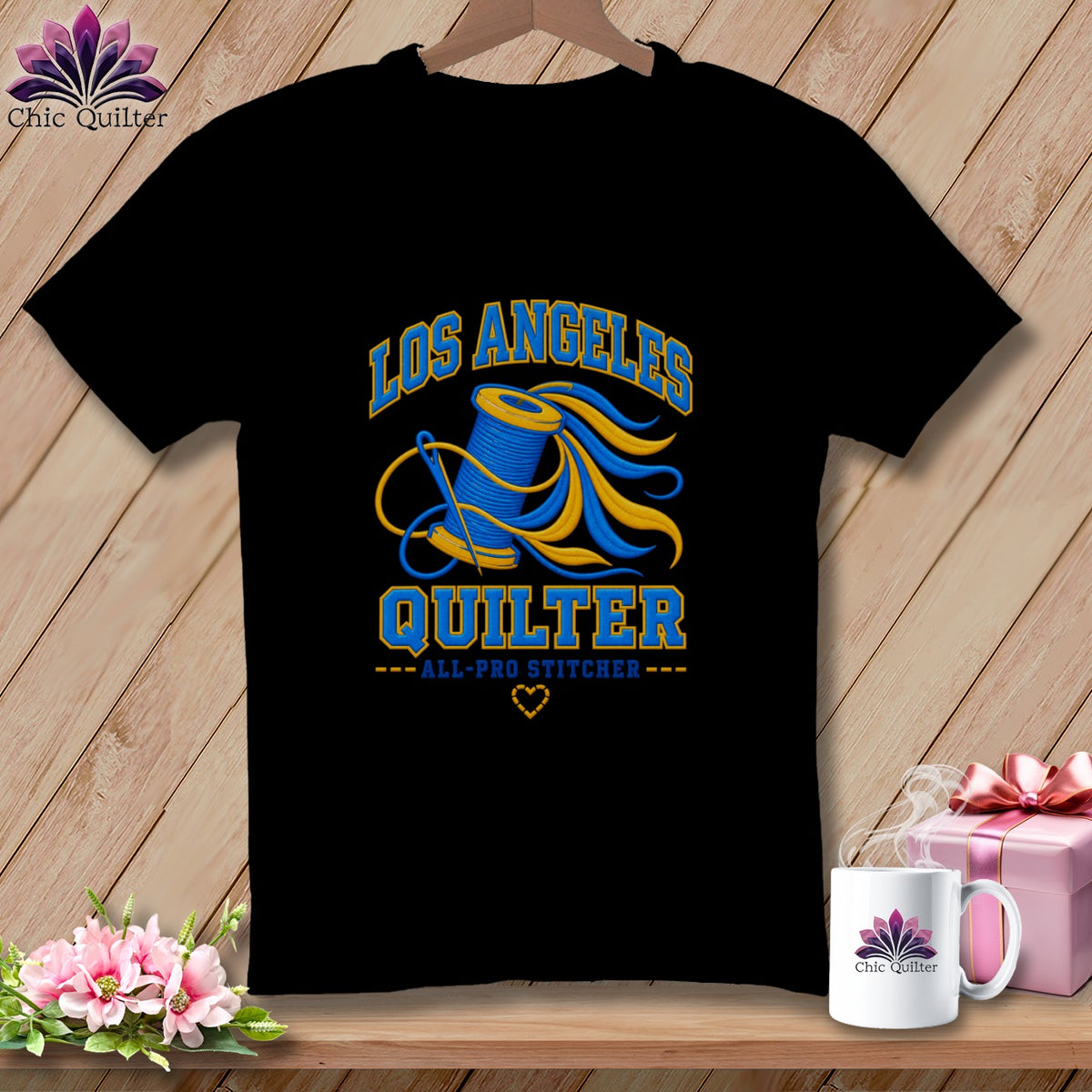 A black crewneck t-shirt featuring a blue and yellow Los Angeles Quilter graphic with a spool of thread and needle.
