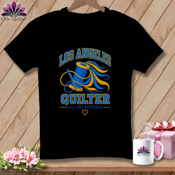 A black crewneck t-shirt featuring a blue and yellow Los Angeles Quilter graphic with a spool of thread and needle.
