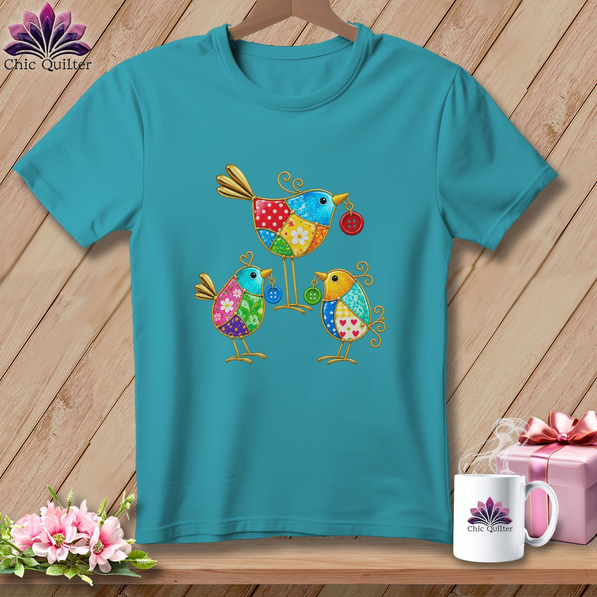 Teal t-shirt featuring a colorful patchwork quilt bird design hanging on a wooden hanger.