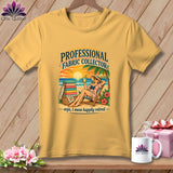A mustard yellow t-shirt with a beach graphic reading Professional Fabric Collector, Oops, I mean happily retired.