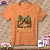Orange t-shirt featuring a forest graphic of animals quilting and the text May The Quilt Be With You.