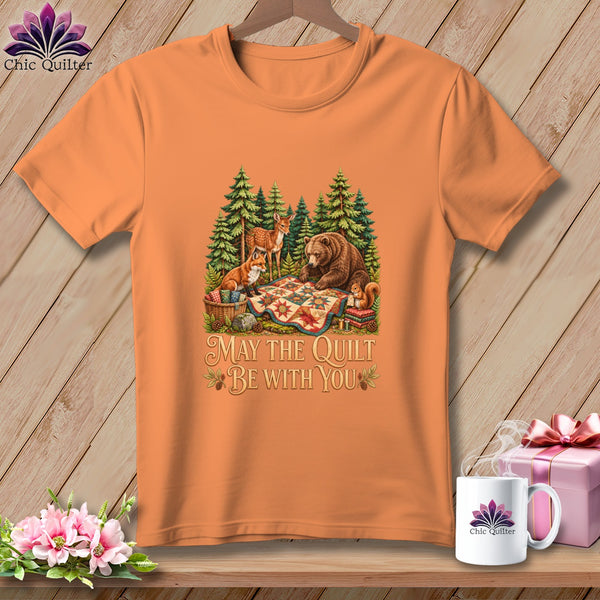 Orange t-shirt featuring a forest graphic of animals quilting and the text May The Quilt Be With You.
