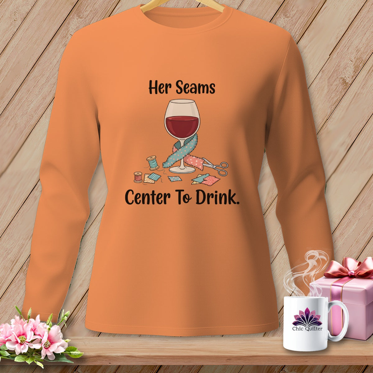 Orange long-sleeve shirt with wine glass, sewing supplies, and text "Her Seams Center To Drink."