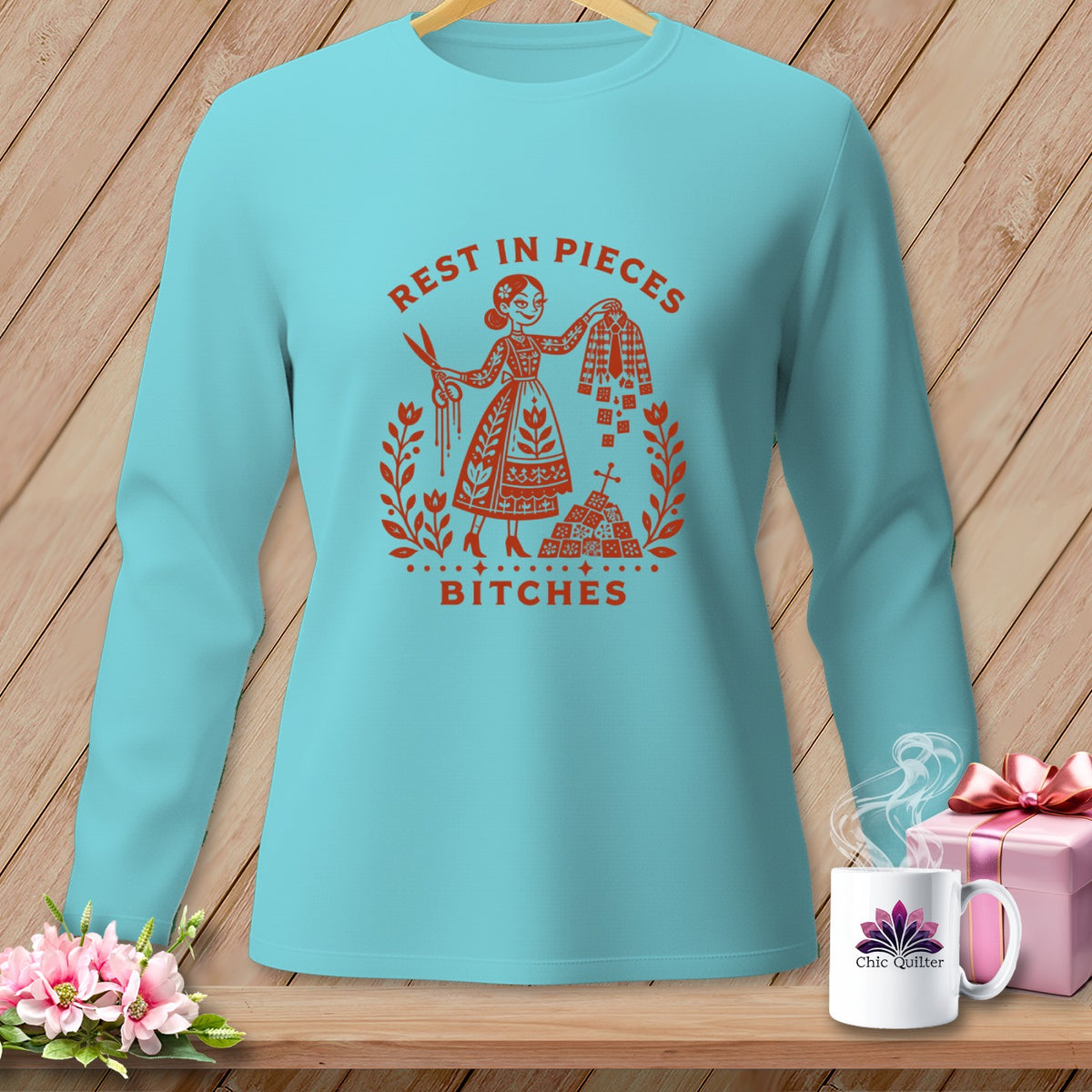 Aqua long-sleeve shirt with red graphic of a woman, scissors, and the text "REST IN PIECES BITCHES".
