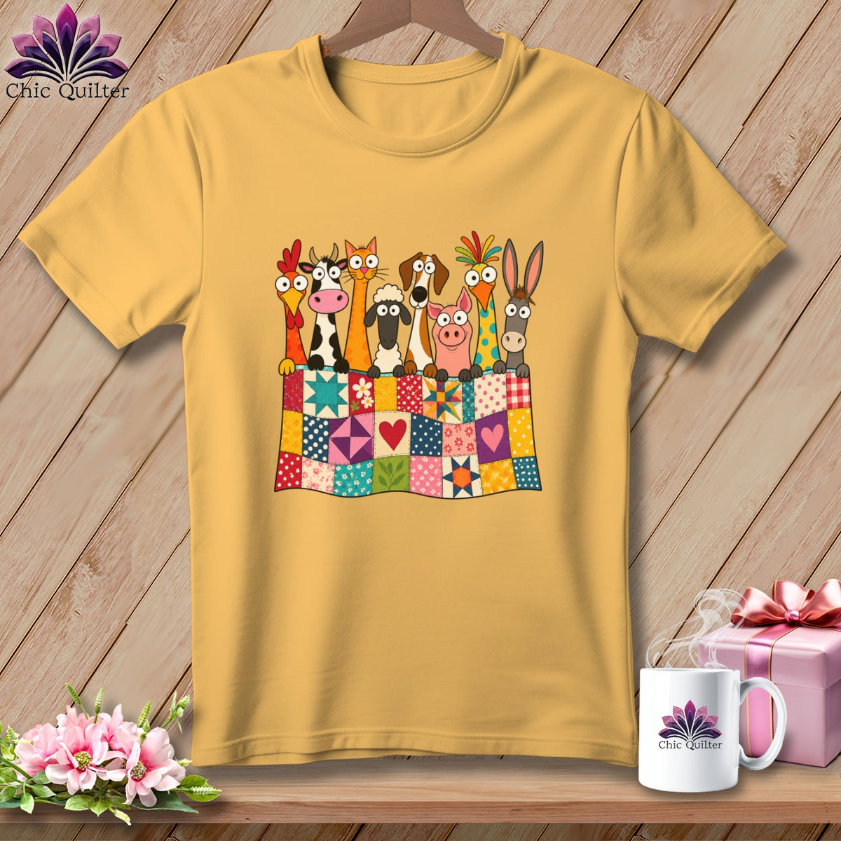 A gold short-sleeved t-shirt features a colorful graphic of cartoon farm animals peeking over a patchwork quilt.